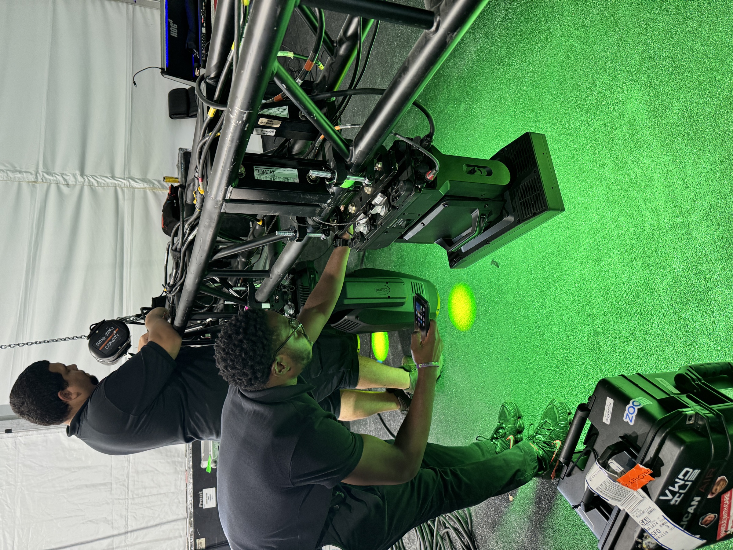 Lighting technicians configuring moving-head fixtures mounted to the event truss