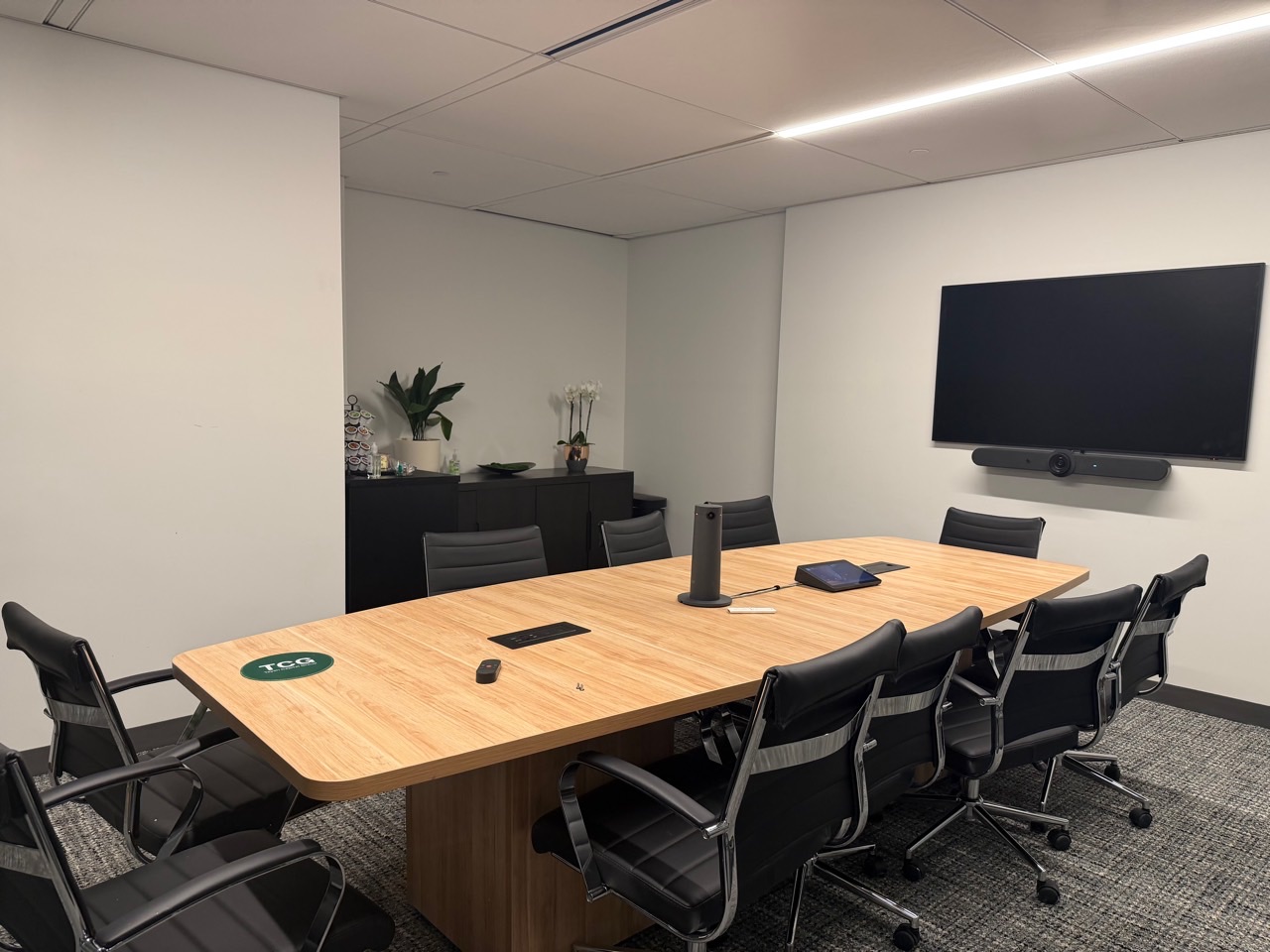 The completed TCG video conference room with a wall-mounted display and Logitech Microsoft Teams system
